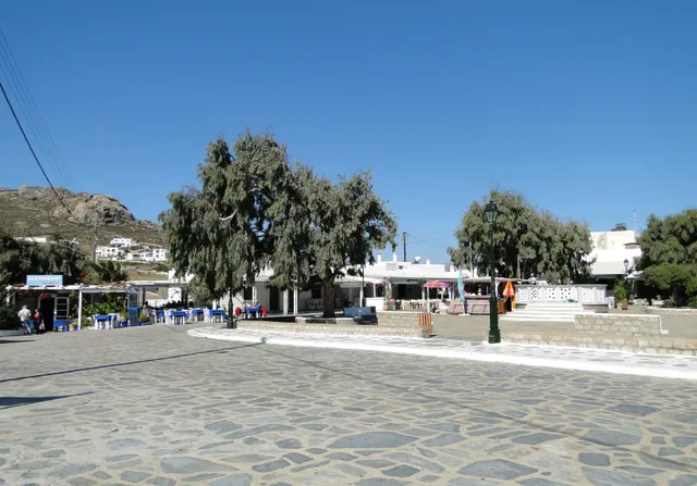 Trees, tables and white buildings around Ano Mera’s central square in October 2011
