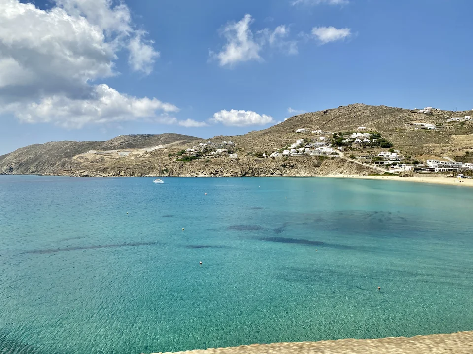 Turquoise water and hillside buildings around Kalo Livadi Bay in May 2023