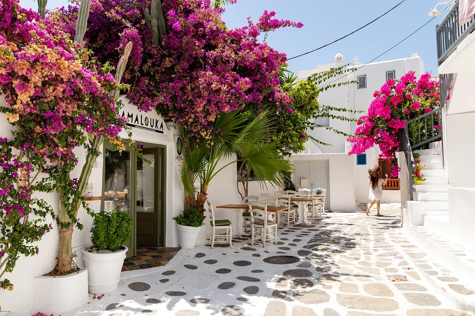 Bougainvillea and outdoor tables along a whitewashed Mykonos Town lane in July 2020