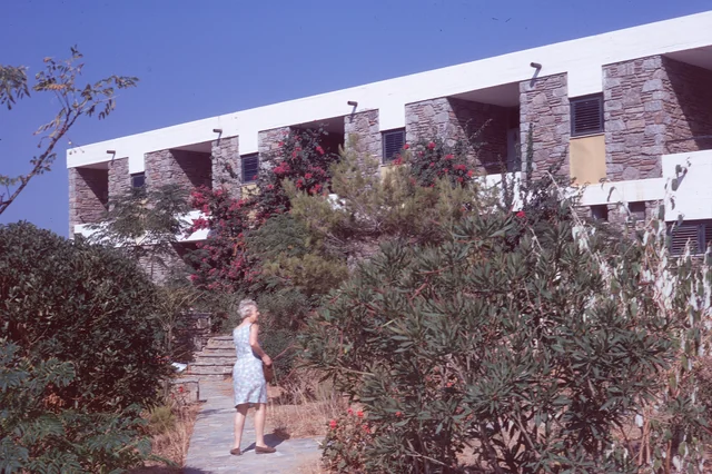 A hotel façade with recessed balconies, stone walls, planting and steps