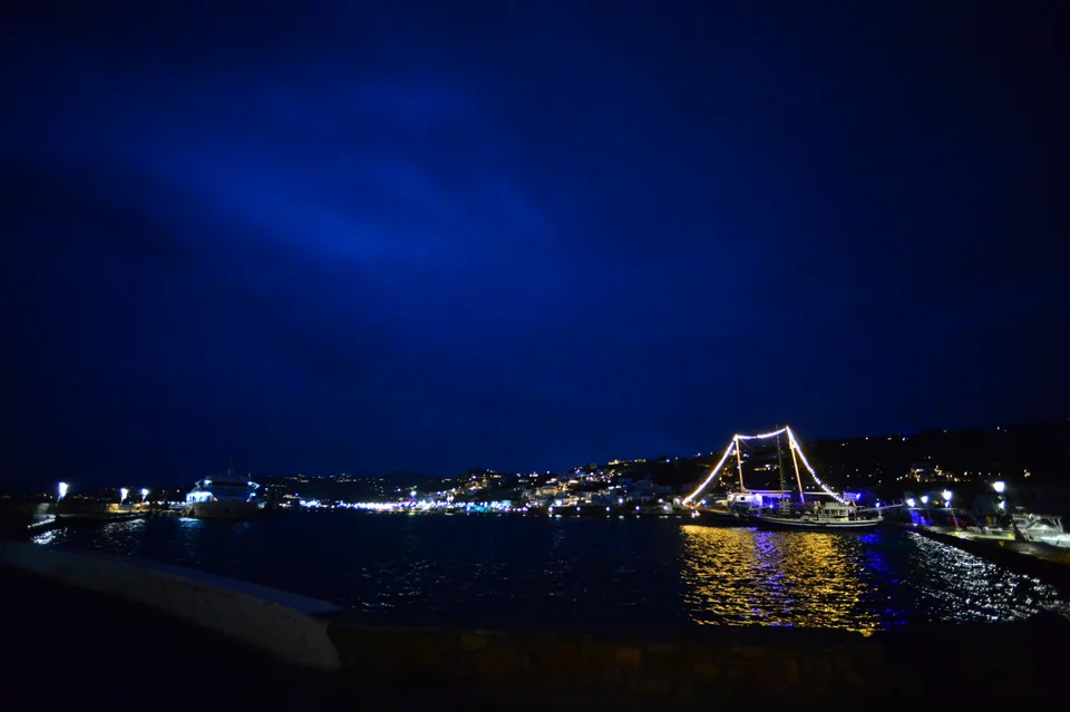 The harbour and illuminated boats beneath a deep blue night sky in Mykonos